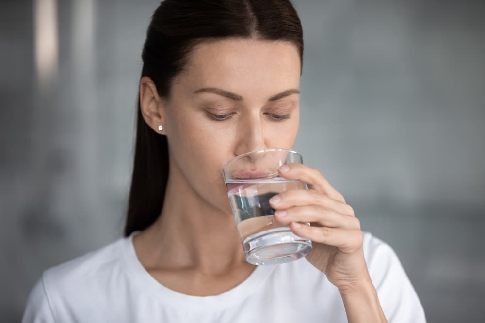 Woman taking a sip of water after using a Myrkl hangover pill