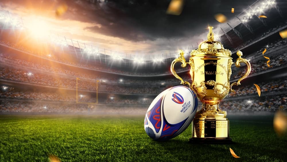 Rugby ball next to the Rugby World Cup on a rugby pitch