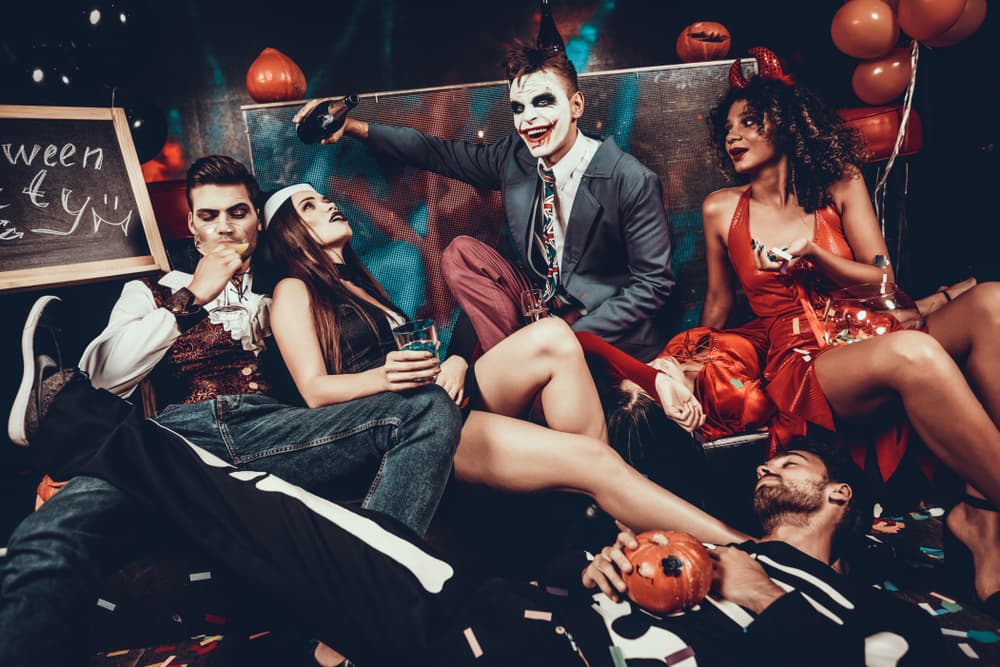 People in costumes at a halloween party having fun experiencing a hangover